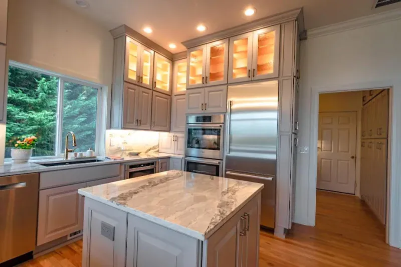 A kitchen with stainless steel appliances and a large island in the middle.