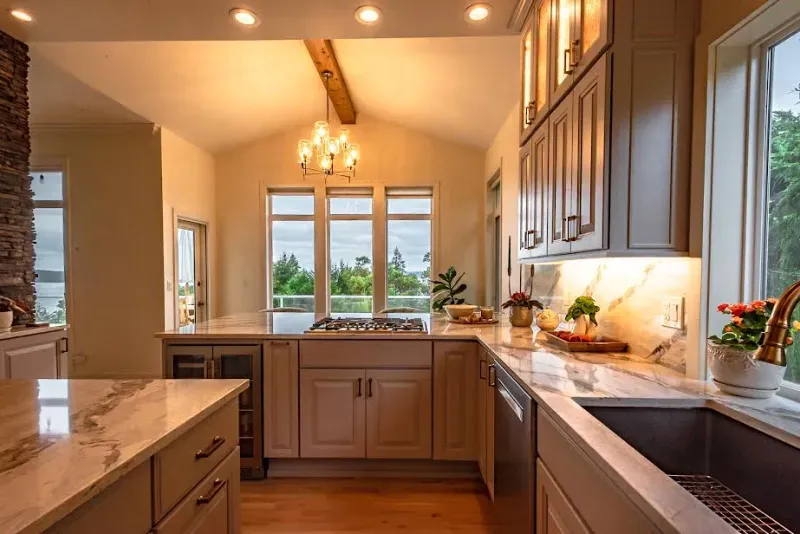 A kitchen with a sink , stove , cabinets , and a large window.