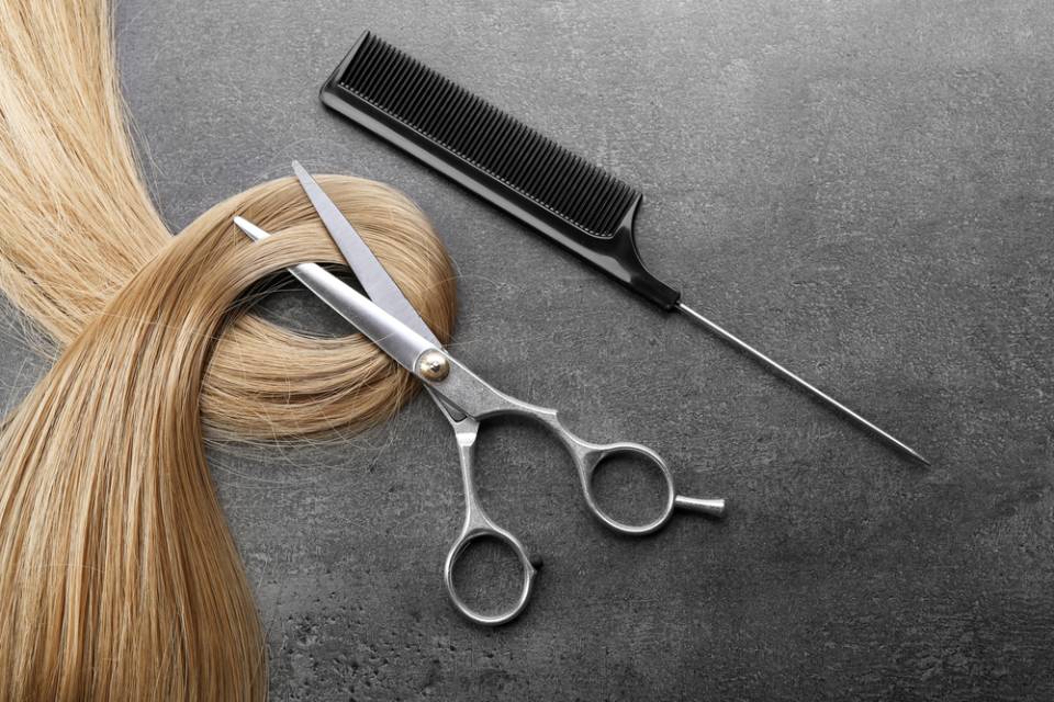 Forbici e pettine impiegati nel taglio di capelli biondi di donna