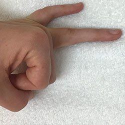 A close up of a person 's hand making a peace sign on a white towel.