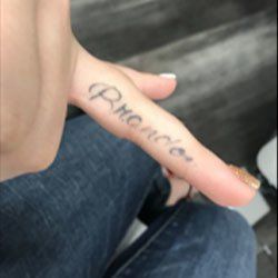 A person has a tattoo on their finger that says promise