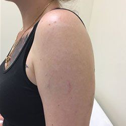 A woman in a black tank top has a tattoo on her arm.