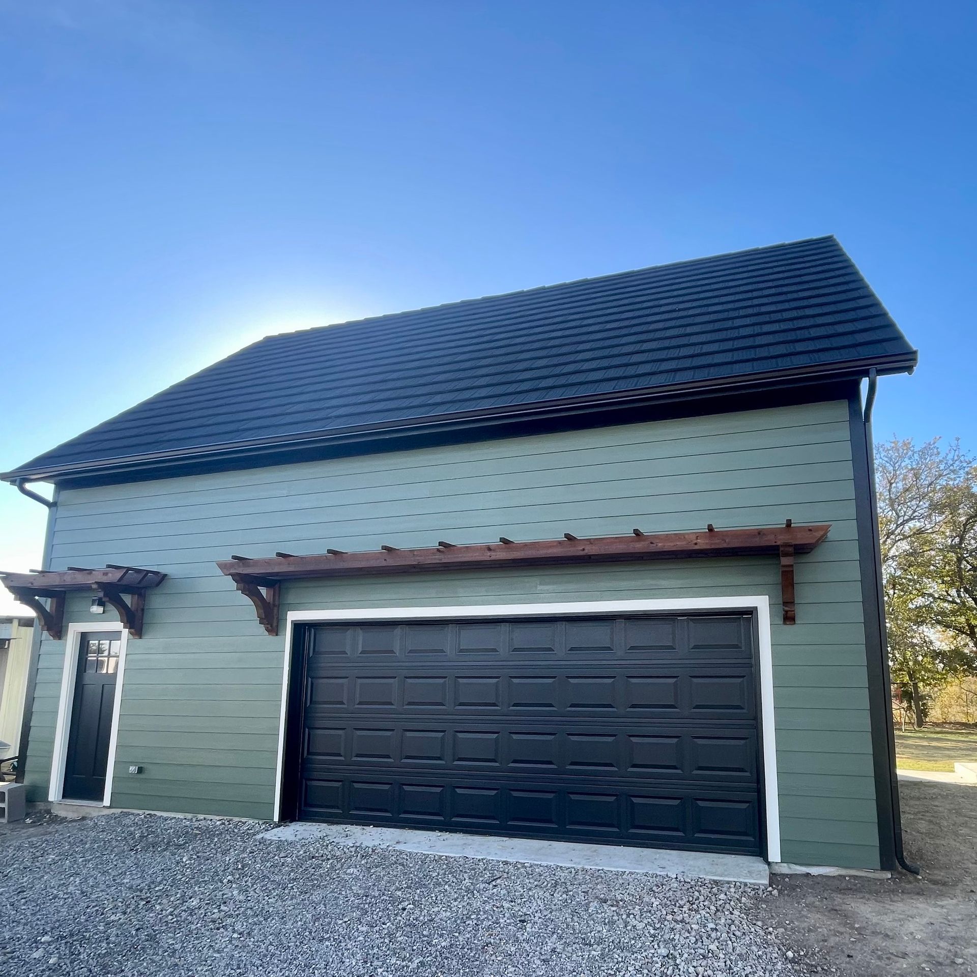 Two-story house with dark roof and black garage door, seen from the front on a sunny day