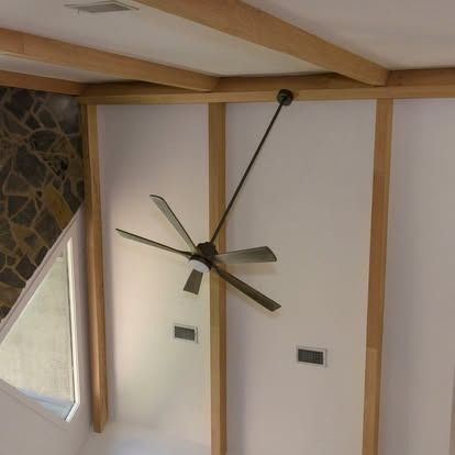Living room wall with a modern ceiling fan and wooden beams, viewed at an angle