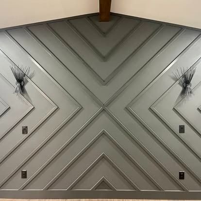 Modern gray accent wall with chevron paneling, wall sconces, and electrical outlets