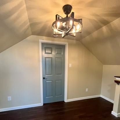 Small room with gray door, dark hardwood floor, and modern black ceiling light fixture.