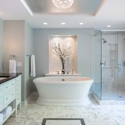 Bright modern bathroom with freestanding tub, glass shower, and light marble finishes