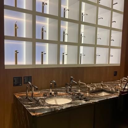 Marble bathroom vanity with two sinks and backlit shelves displaying faucets