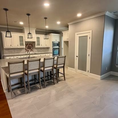 Modern kitchen with white cabinets, gray tile floor, island seating, and pendant lights