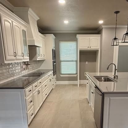 Bright white kitchen with island sink, gray countertops, tile floor, and window blinds.