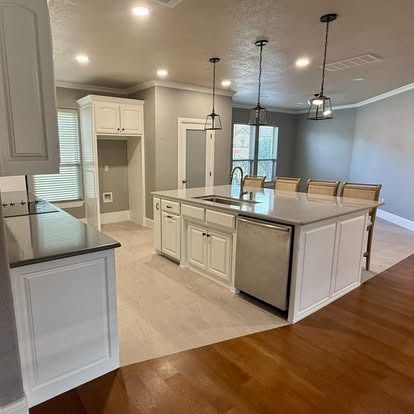 Bright modern kitchen with white cabinets, island, stainless appliances, and dining area beyond.
