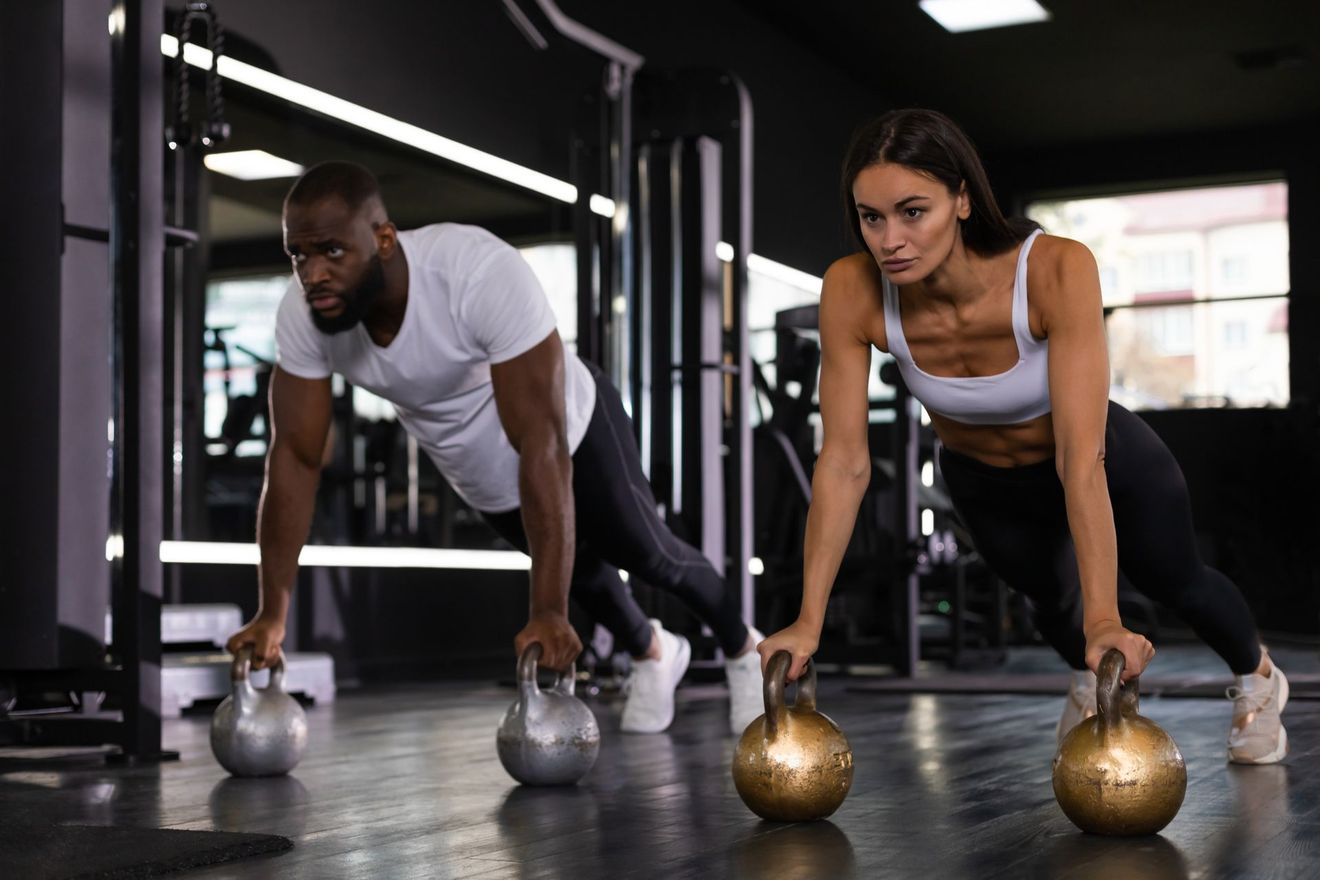 man and woman working out with kettle balls