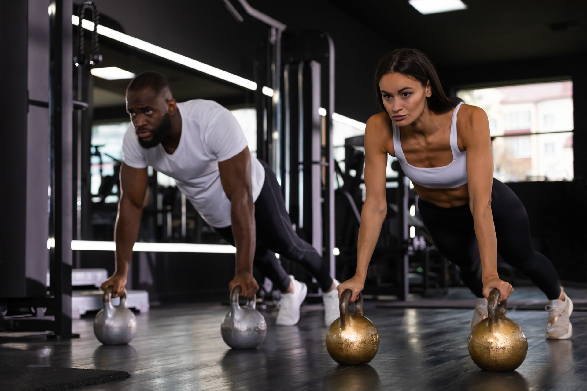 man and woman working out using kettle balls