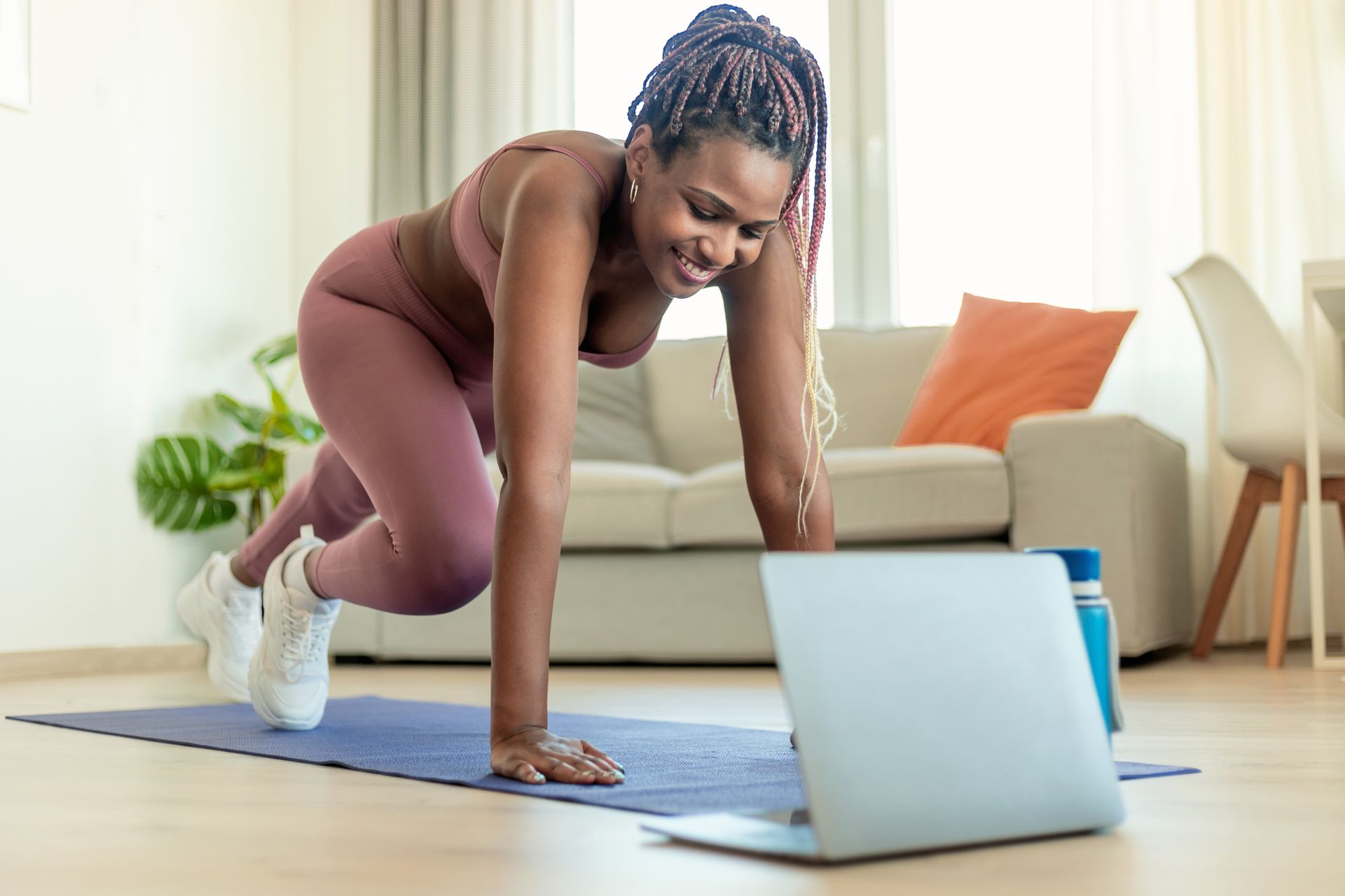 woman working out at home using laptop