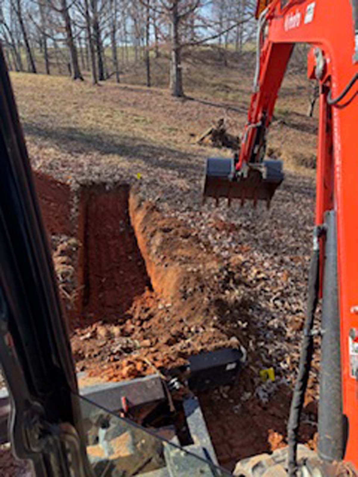 A red excavator is digging a hole in the ground.