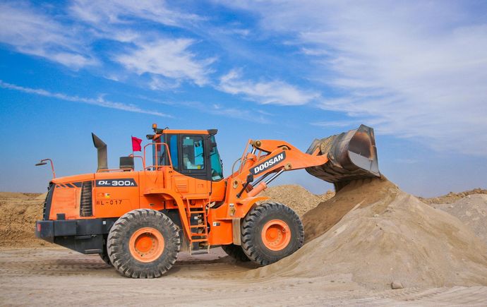 A bulldozer is loading sand into a pile.