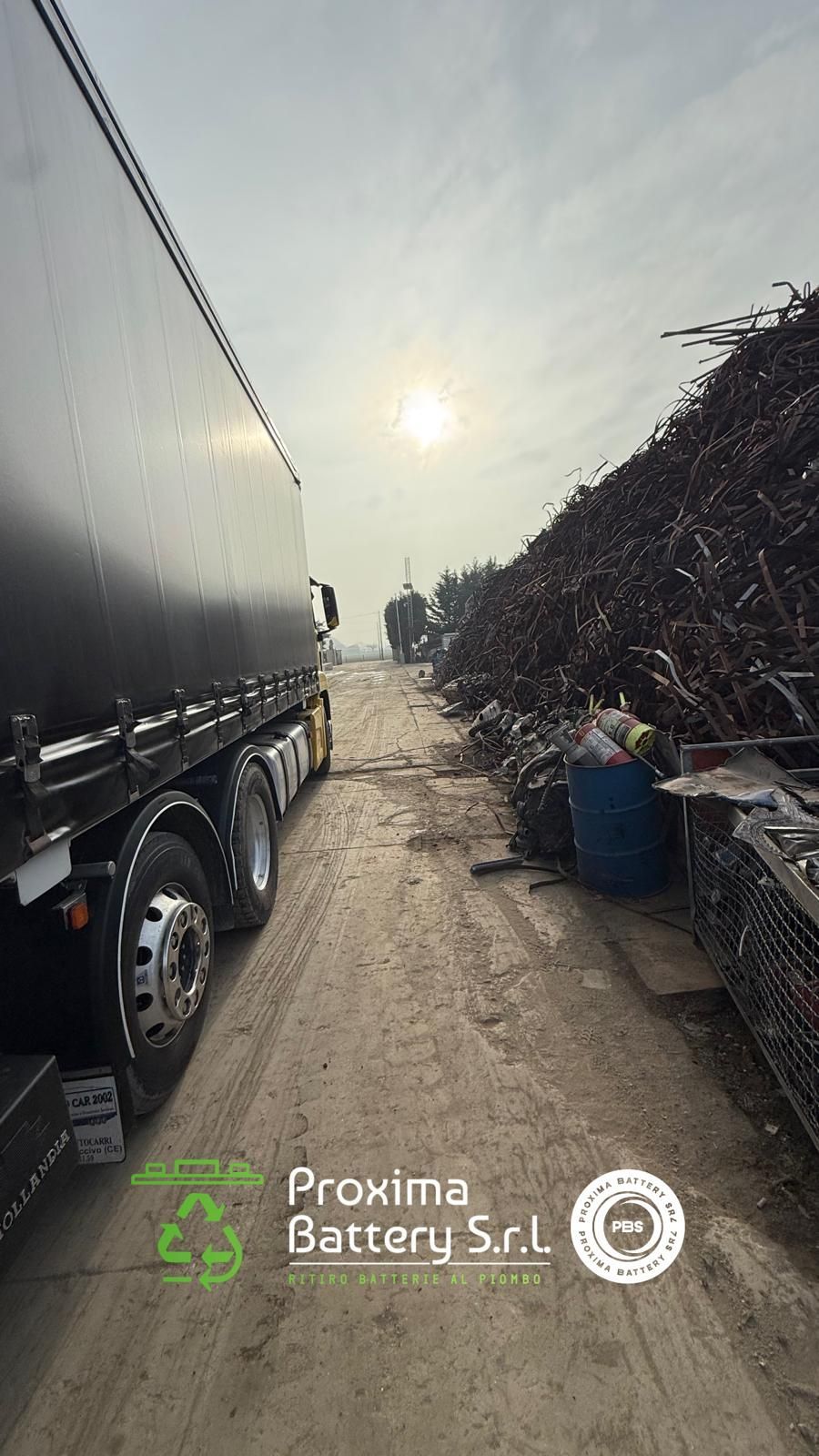 Un camion con cassone aperto parcheggiato vicino a un container di batterie presso il deposito di rottami industriali della Proxima Battery Srl.