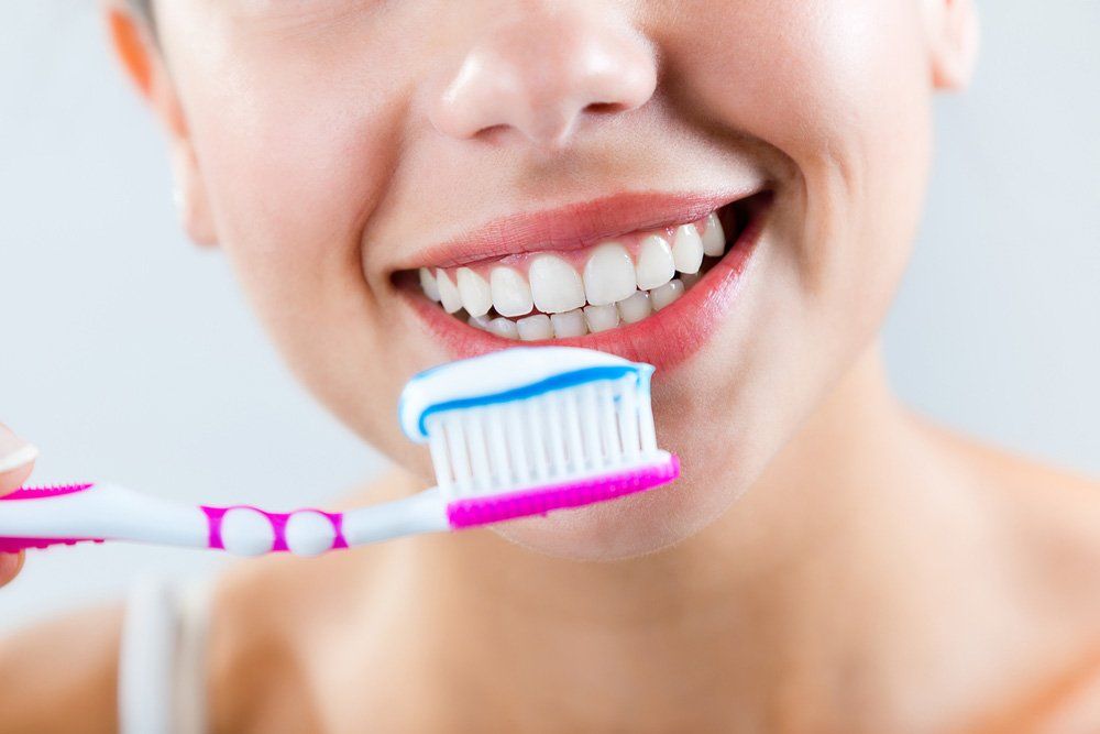 Young Woman Smiling & Holding Pink Toothbrush