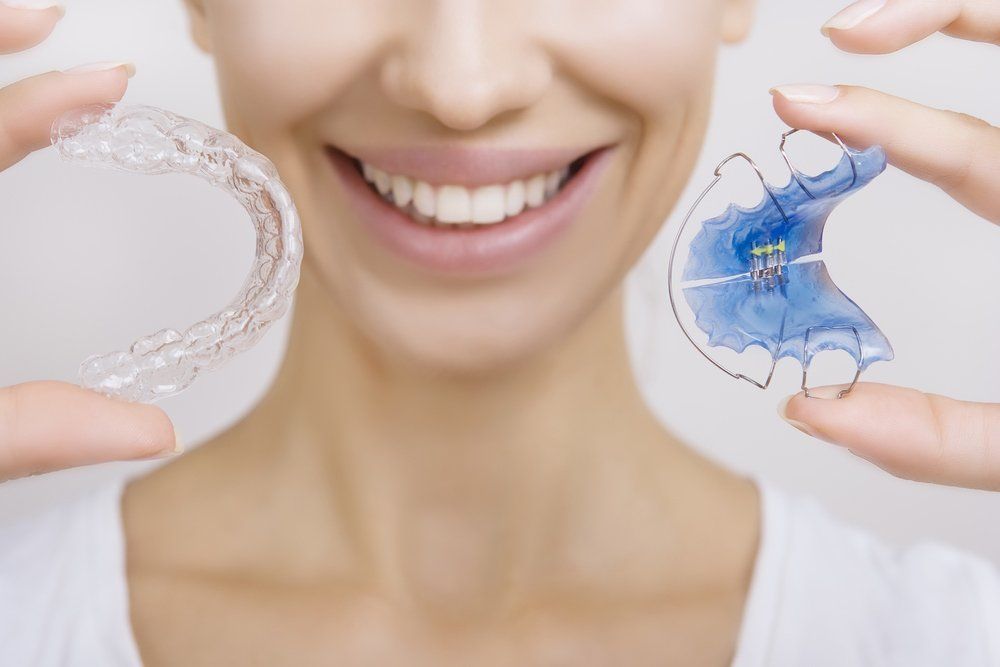 Woman Smiling & Holding Retainers