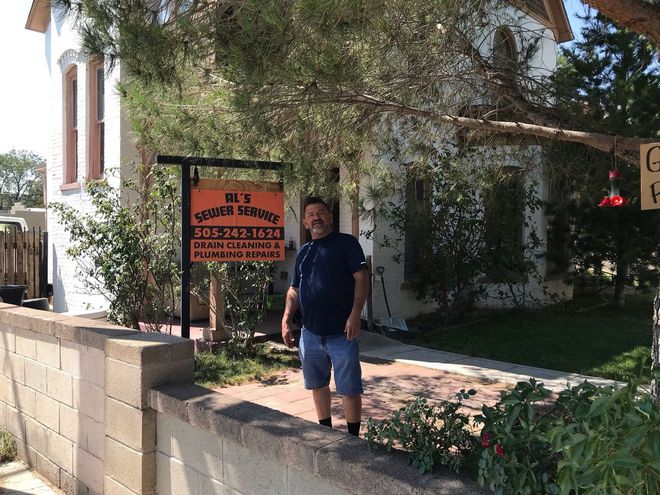 A Man is Standing in Front of a House with a for Sale Sign — Albuquerque, NM — Al's Sewer Service