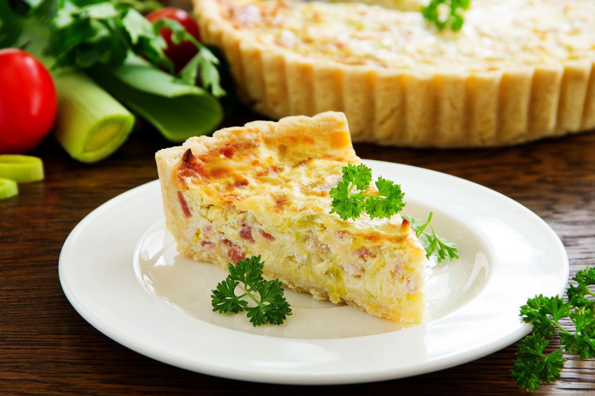 A slice of quiche is on a white plate.