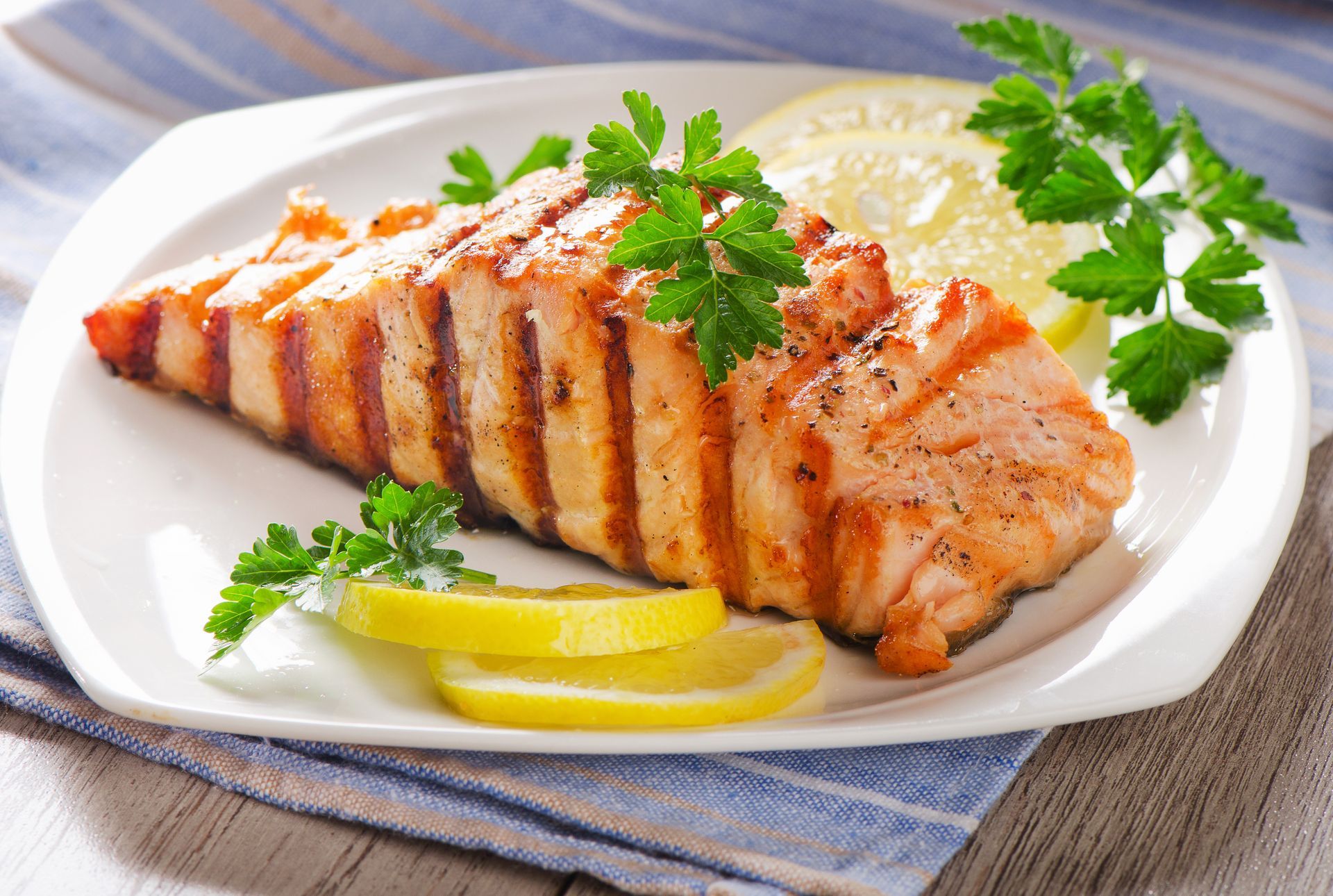 A white plate topped with grilled salmon and lemon slices