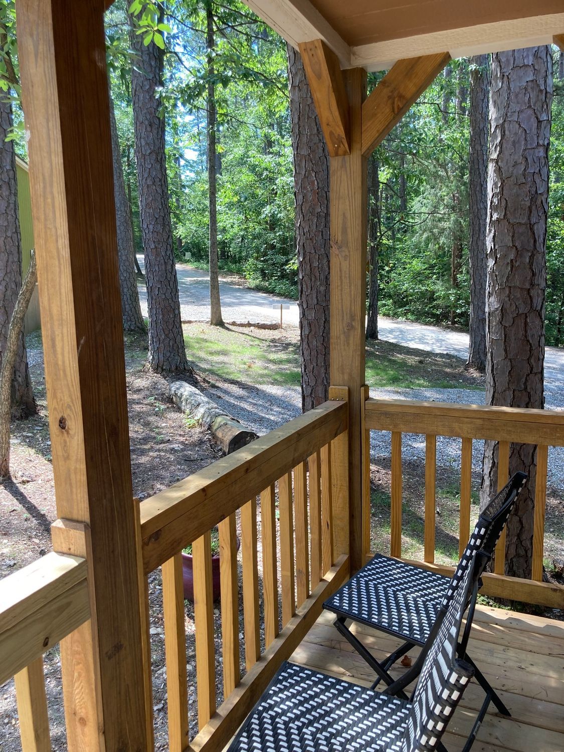 A wooden porch with a chair and ottoman in the woods.