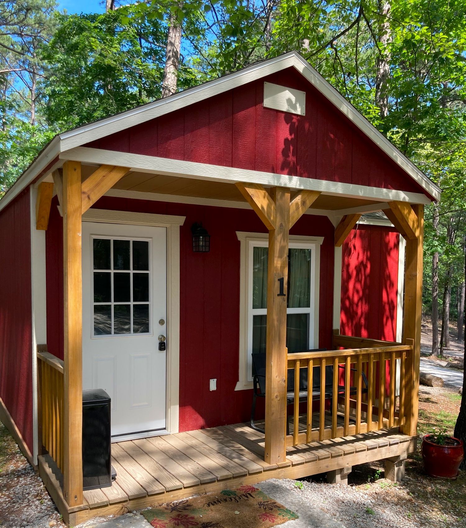 A small red house with a porch in the woods