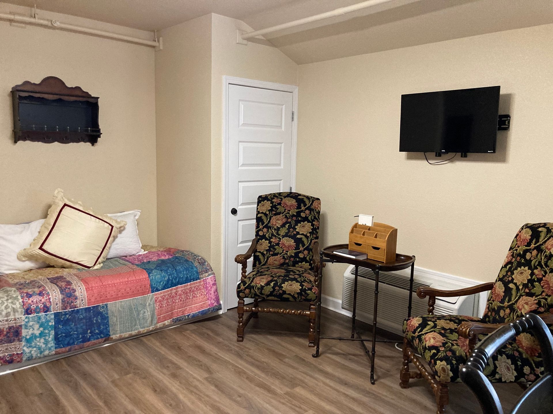 A living room with a bed , chairs , and a flat screen tv.