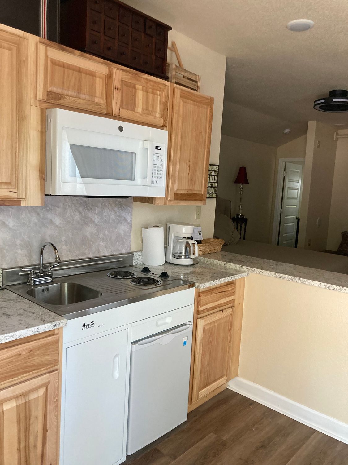 A kitchen with wooden cabinets , a microwave , a sink , and a dishwasher.