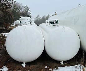 Two white propane tanks are sitting next to each other in the snow.