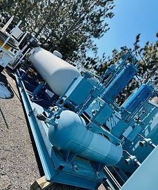 A bunch of blue tanks are sitting on top of each other in a field.