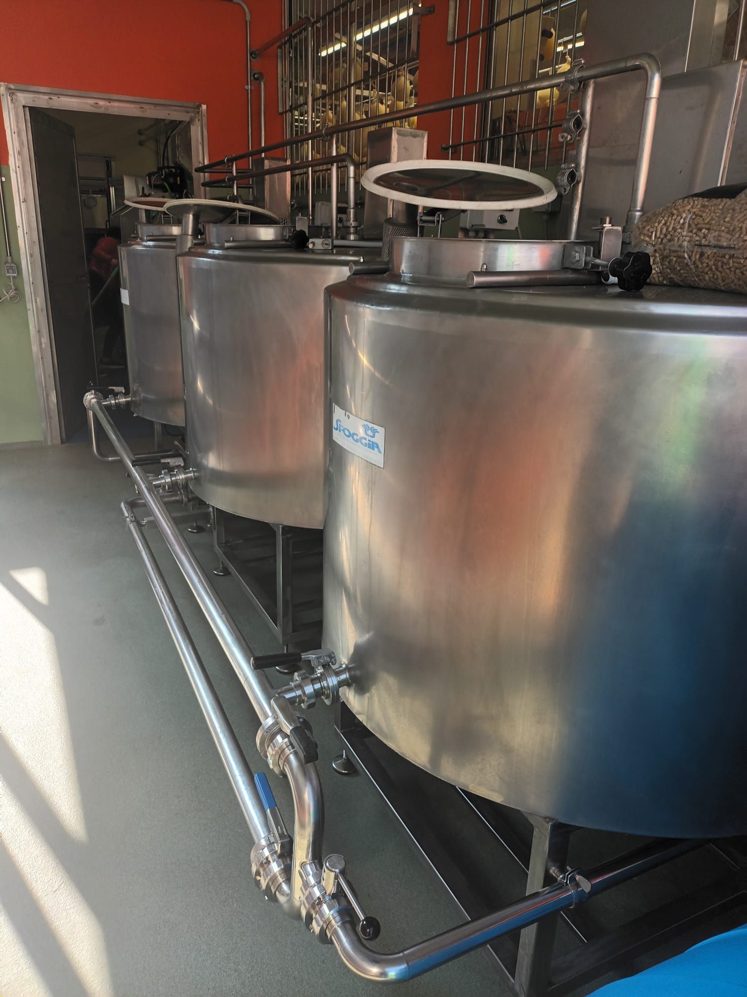 In una fabbrica sono allineate una fila di serbatoi in acciaio inox.