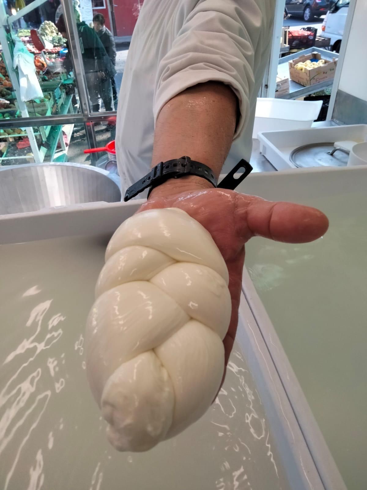 Una persona tiene in mano un pezzo di mozzarella