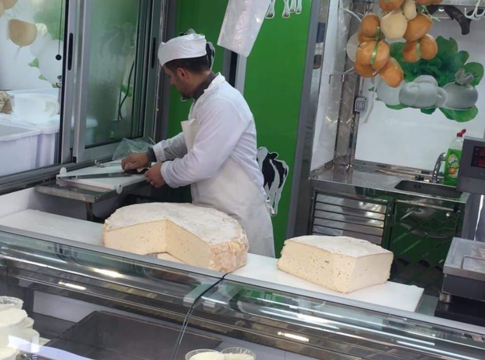 Un uomo in grembiule taglia un pezzo di formaggio