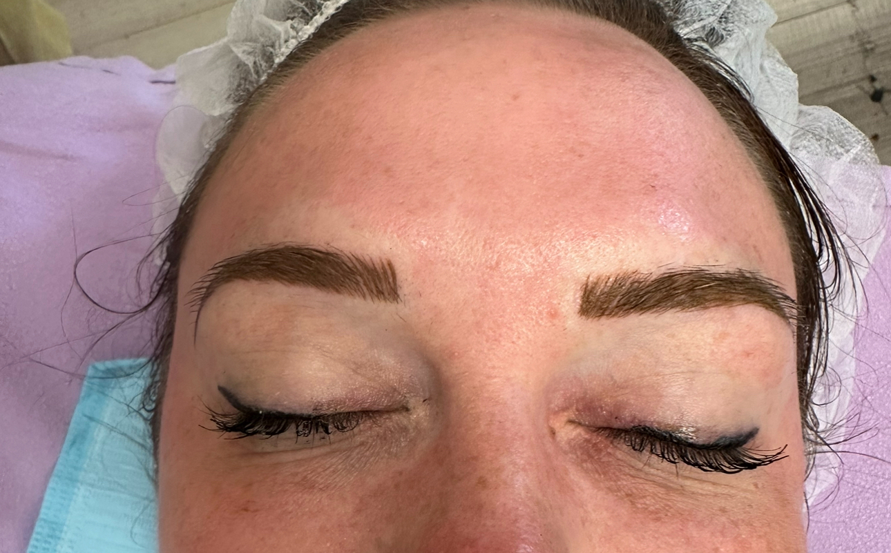 Woman with closed eyes, fresh eyebrow tattoo. Brown brows, eyeliner, light skin.