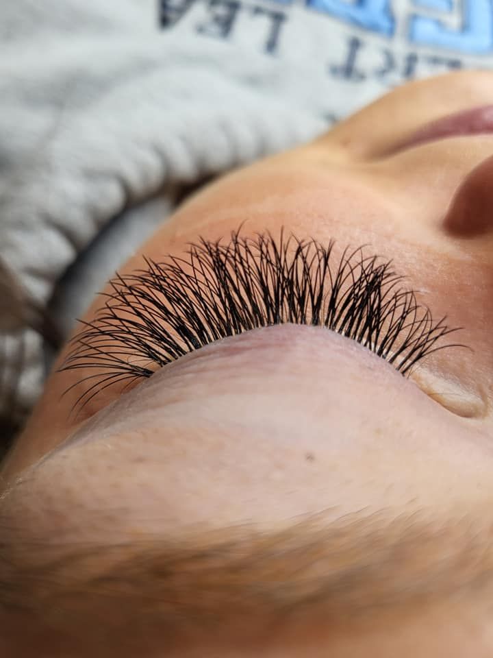 Close-up of a person's closed eye, showcasing long, black lash extensions.