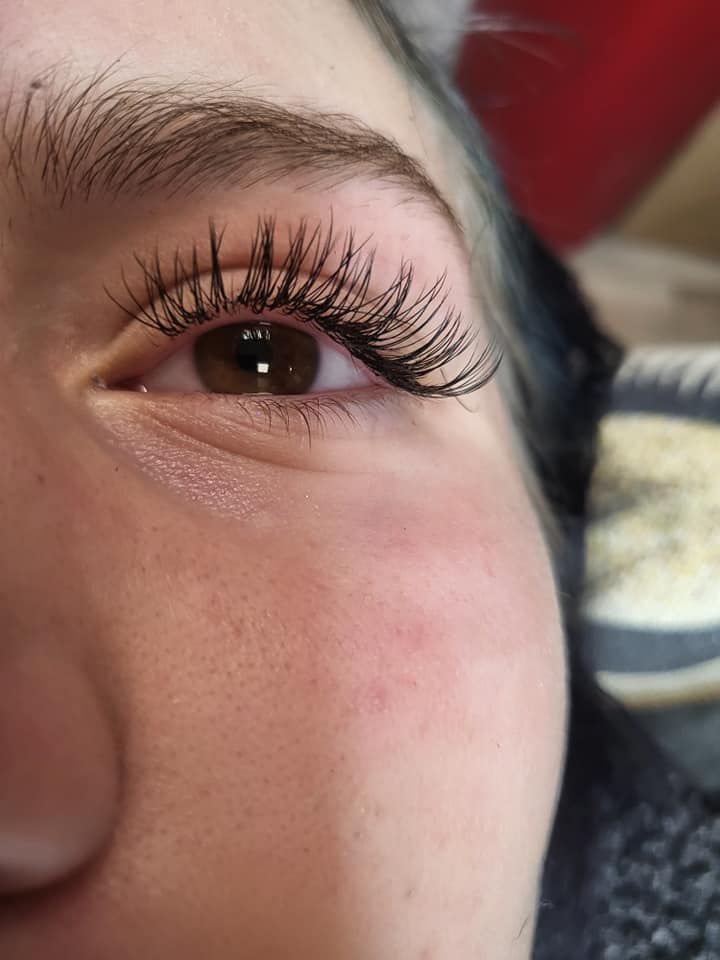 Close-up of an eye with long, dark eyelashes. Brown iris, fair skin, light eyebrow.