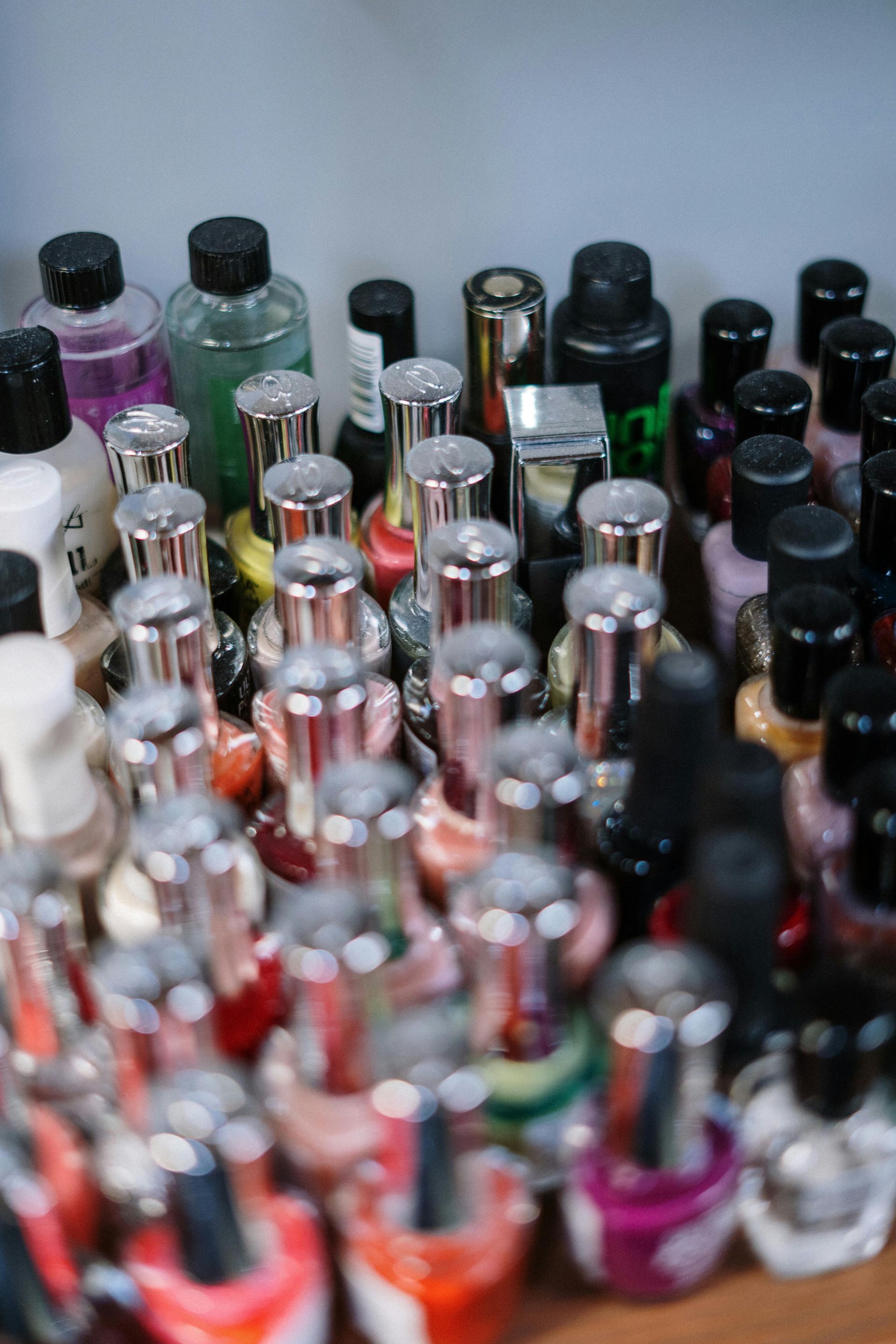 Bottles of nail polish in various colors, tightly packed together on a shelf.