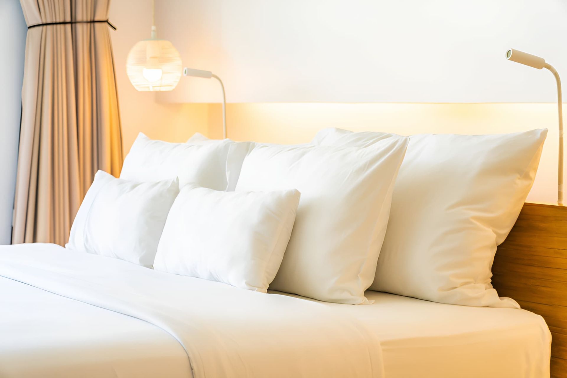 A Bed With White Sheets and Pillows in a Hotel Room — Bryants Beds and Mattresses In Lismore, NSW