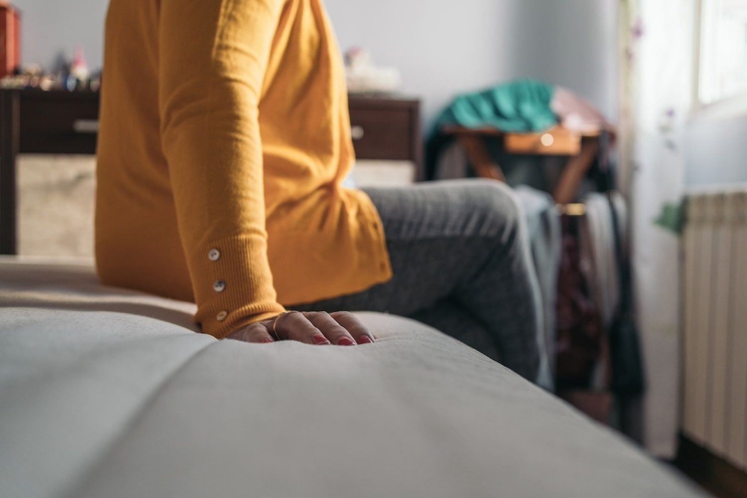 Woman in a Yellow Sweater is Sitting on a Bed — Bryants Beds and Mattresses In Lismore, NSW