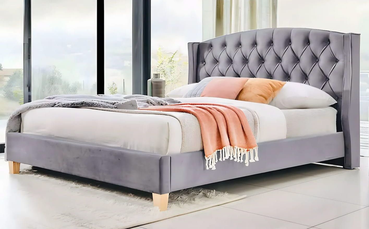 A Bed With a Tufted Headboard is Sitting in Front of a Window — Bryants Beds and Mattresses In Lismore, NSW