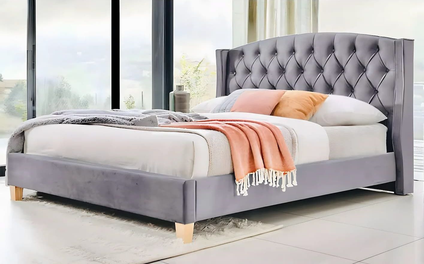 A Bed With a Tufted Headboard is Sitting in Front of a Window — Bryants Beds and Mattresses In Lismore, NSW