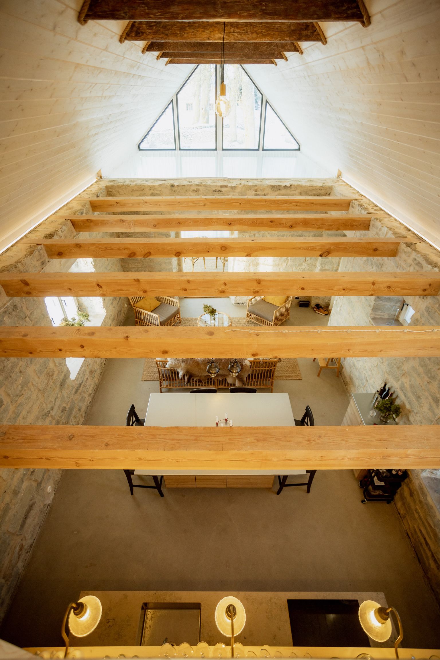 Interior of a rustic building with wooden beams and a triangular window.