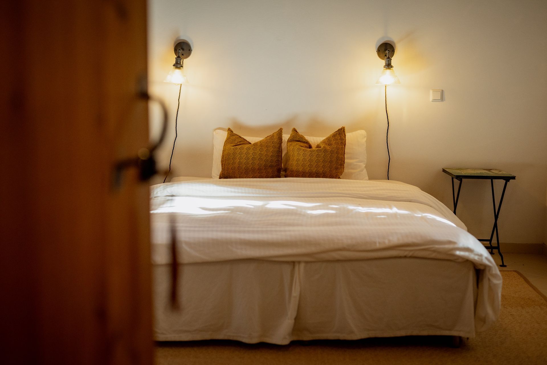 Bedroom interior with a bed, two pillows, and wall-mounted lamps.