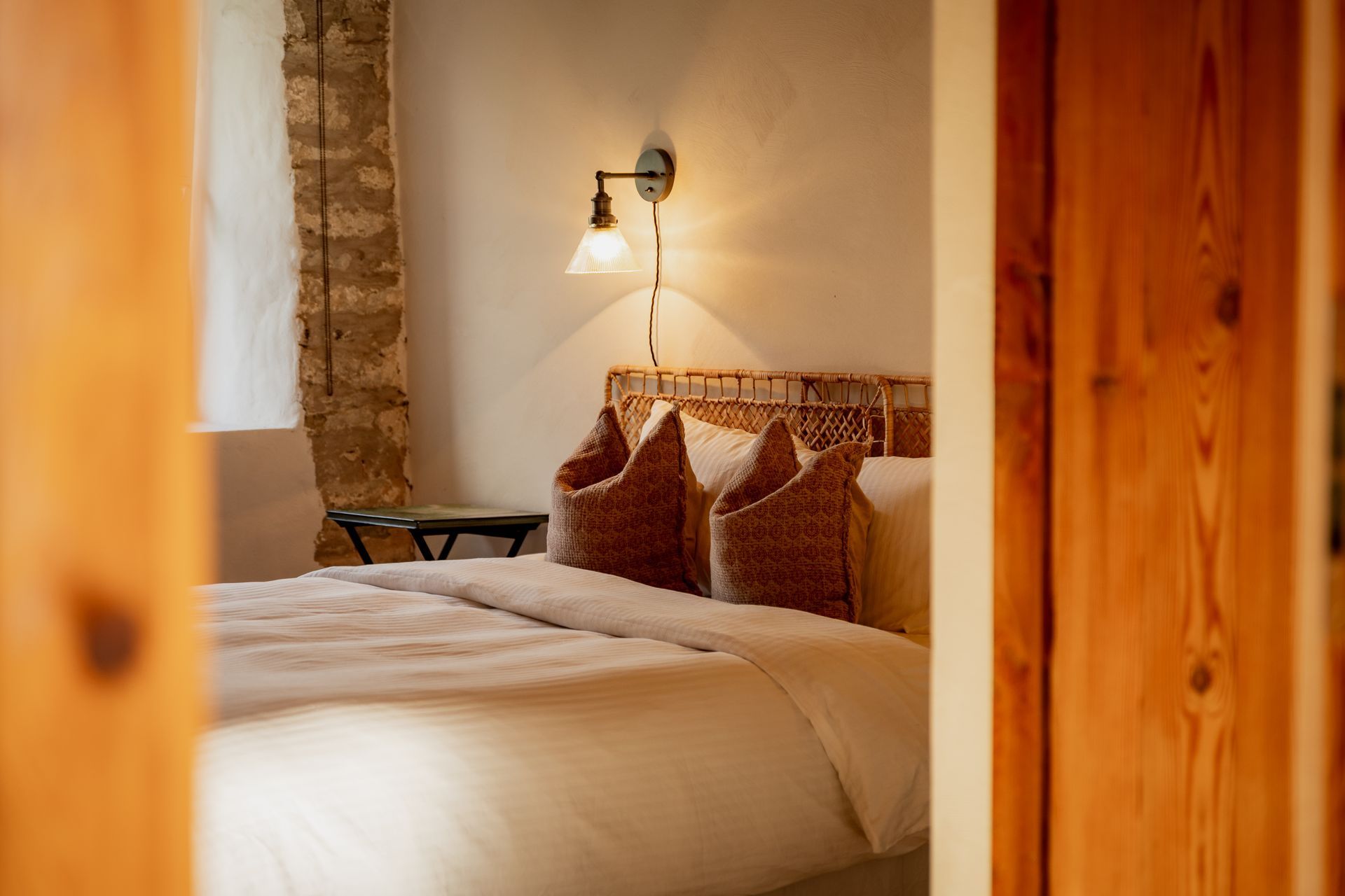 Bedroom interior with a bed, wicker headboard, and wall-mounted lamp.