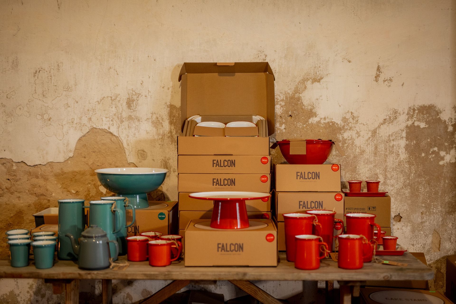 Bottles of wine on shelves, some with red and green labels, others with red tops. Empty wine glasses sit in front.