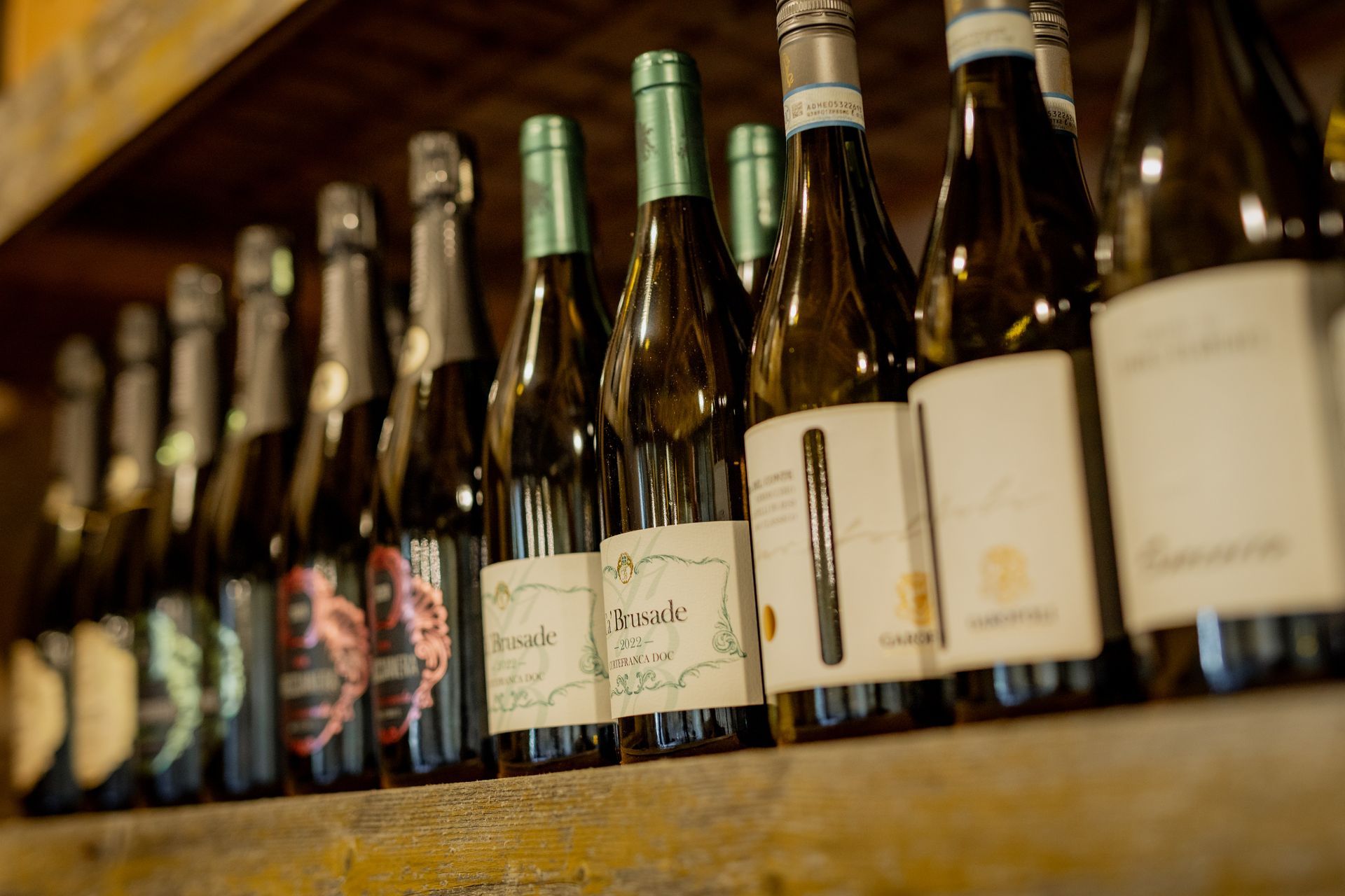 Wine bottles lined up on a shelf, various labels.