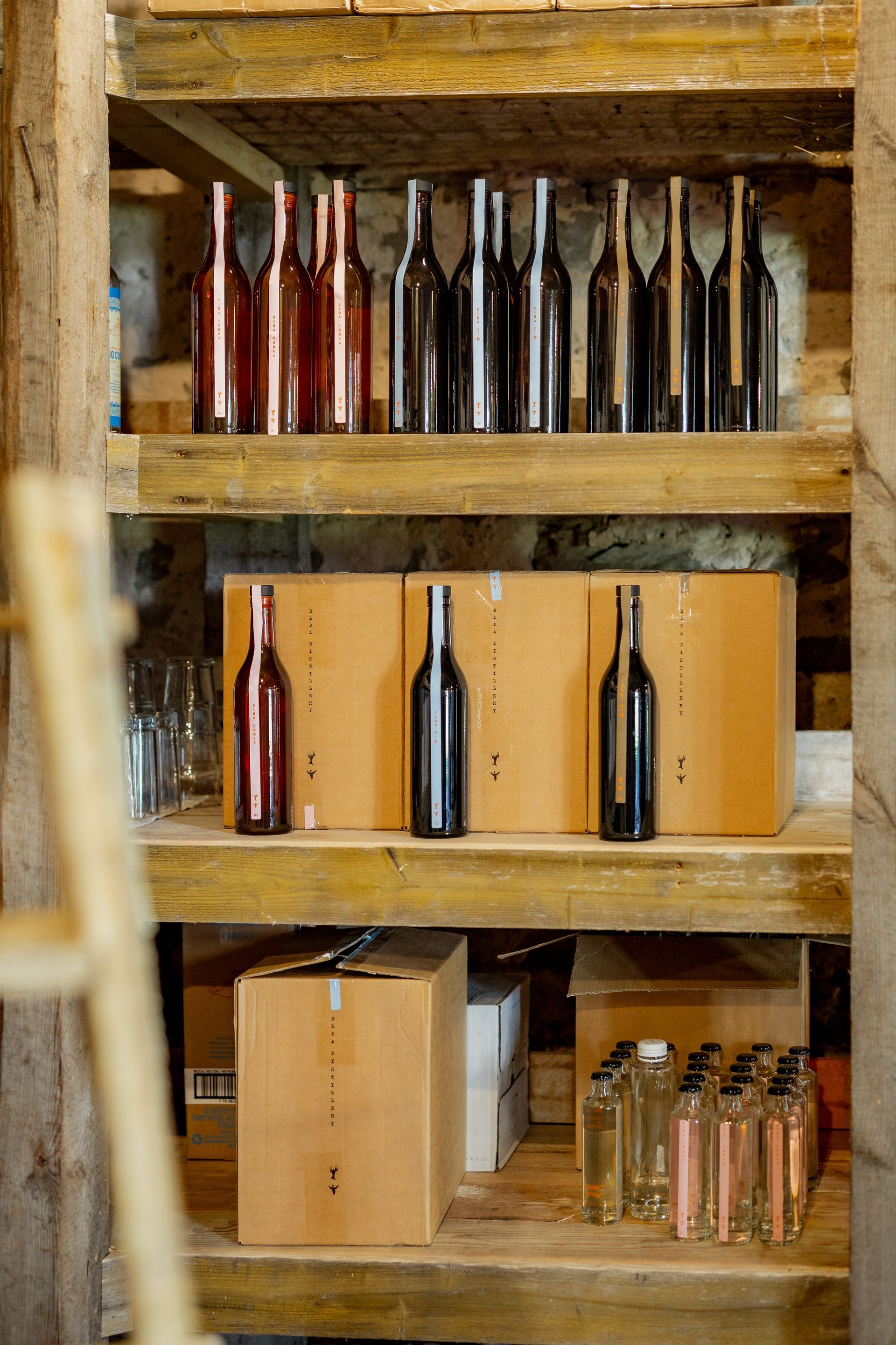 Wine bottles on wooden shelves in a rustic cellar setting.