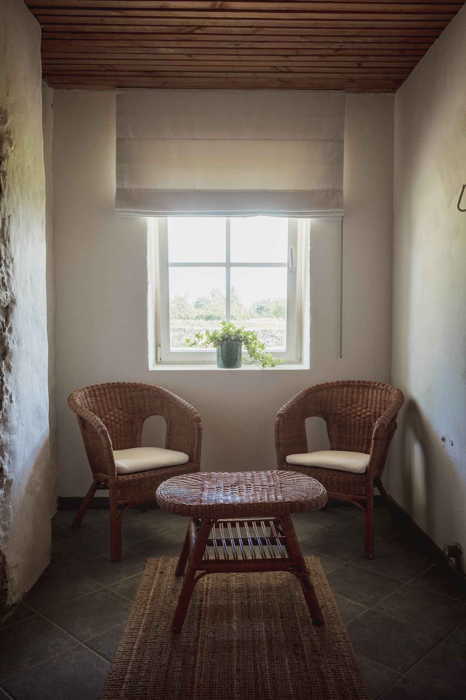 Cozy seating area with wicker chairs and small table in front of a window.